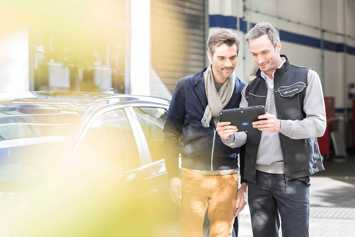 zu sehen ist ein Mitarbeiter, der einem Kunden auf dem Tablet etwas zeigt