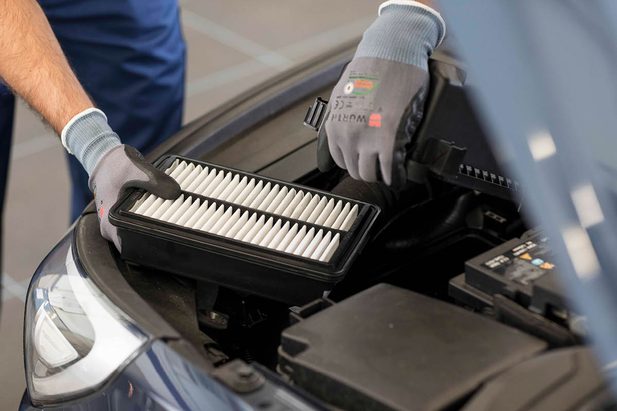 zu sehen ist ein KFZ Mitarbeiter, der die Klimaanlage eines Autos prüft