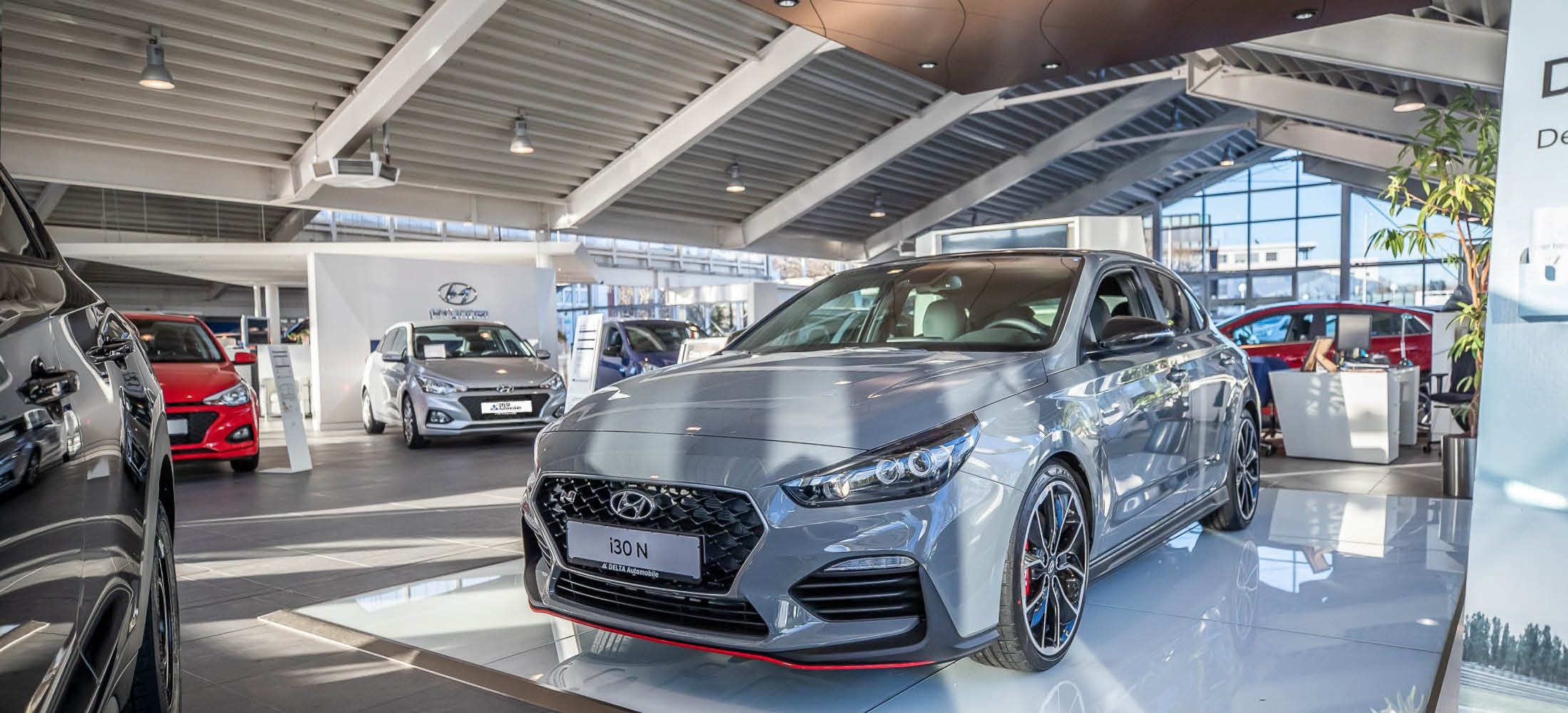 zu sehen ist die Verkaufsfläche von Delta Automobile. Im Vordergrund ist ein grauer Hyundai i30 N