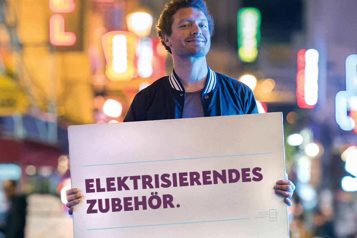 zu sehen ist ein Mann mit Schild: Elektrisierendes Zubehör