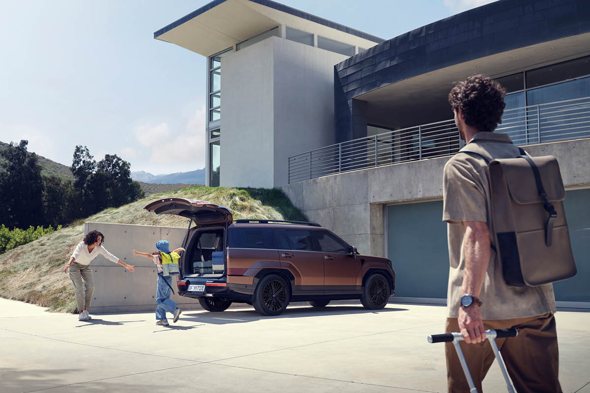 zu sehen ist ein Hyundai SANTA FE mit geöffneten Kofferraum vor einem Haus