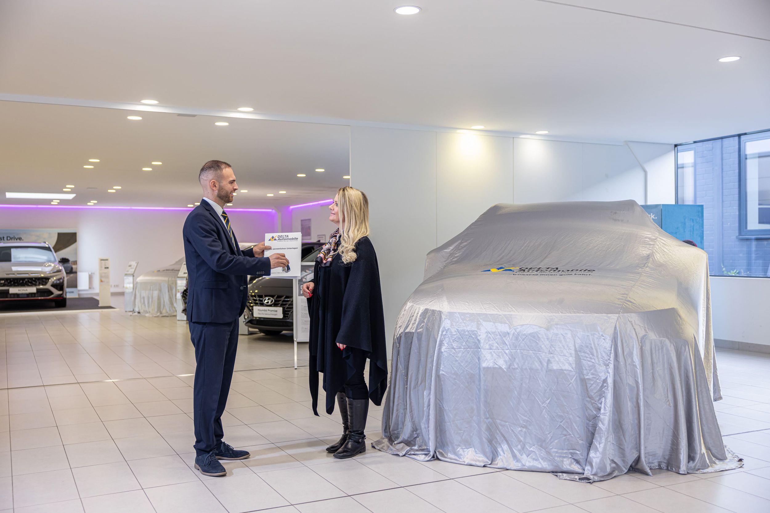 zu sehen ist ein Berater, der eine Frau im Autohaus kompetent berät